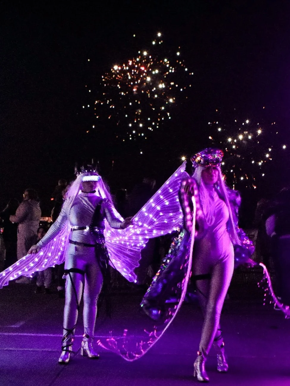 Illuminated characters beneath fireworks at an evening event